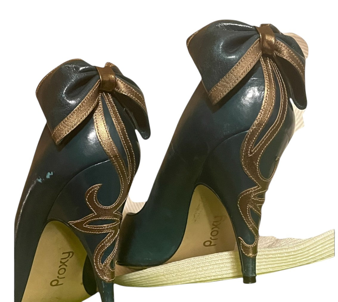 Recycle Me Fancy Proxy teal green patent pumps featuring an oversized bronze bow and decorative swirl stitching